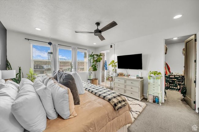 Bedroom with light carpet, a spacious closet, a textured ceiling, ceiling fan, and recessed lighting | Image 22