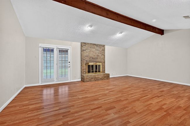Unfurnished living room featuring light wood-style floors, a textured ceiling, and a brick fireplace | Image 5