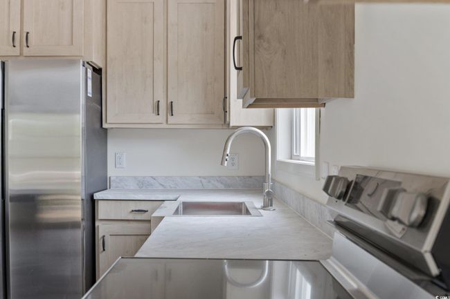 Kitchen with freestanding refrigerator, light brown cabinetry, and light countertops | Image 16