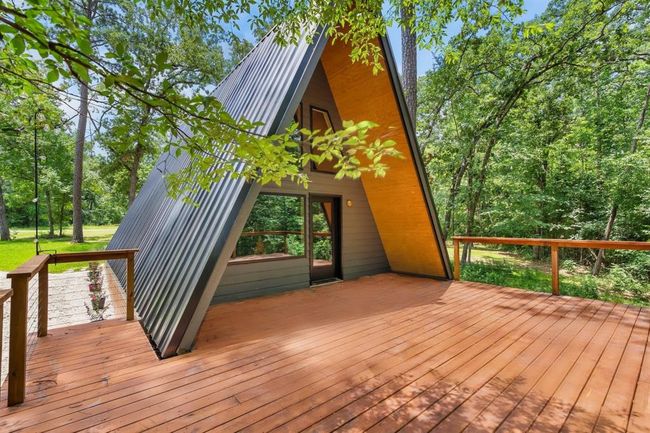 This photo shows a serene outdoor space under a wooden deck, featuring a hammock and a stone path, surrounded by lush greenery, perfect for relaxation and enjoying nature. | Image 26