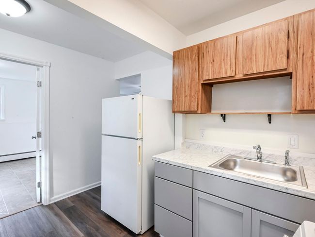 Kitchen with a baseboard heating unit, sink, gray cabinets, white fridge, and dark hardwood / wood-style flooring | Image 19