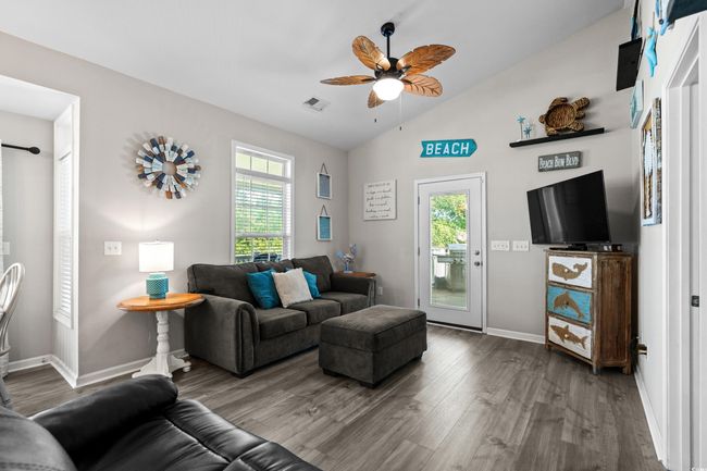Living area featuring visible vents, baseboards, wood finished floors, ceiling fan, and high vaulted ceiling | Image 17