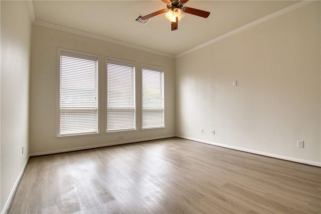 Unfurnished room featuring crown molding, a ceiling fan, wood finished floors, baseboards, and visible vents | Image 16