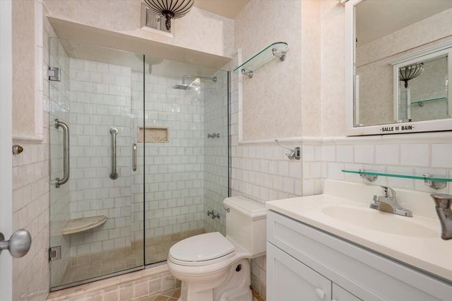 Bathroom featuring a shower stall, toilet, vanity, and tile walls | Image 16