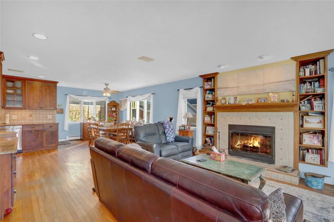 Living room featuring light hardwood / wood-style floors, baseboard heating, ceiling fan, and a fireplace | Image 9