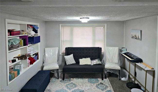 Sitting room with a textured ceiling and carpet flooring | Image 18