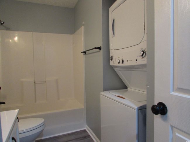 Bathroom with stackable washer and dryer and dark LVP flooring. | Image 16