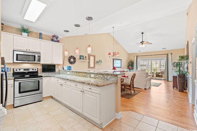 Kitchen with appliances with stainless steel finishes, a peninsula, light tile patterned floors, open floor plan, and a ceiling fan | Image 18