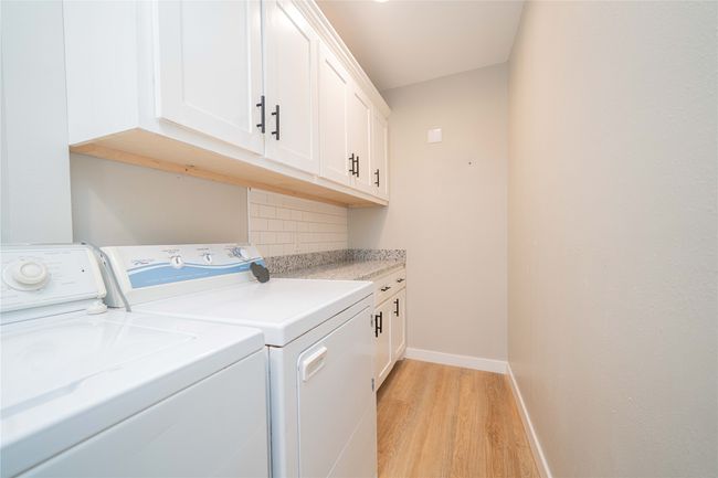 Laundry room featuring washer and dryer, light wood finished floors, and cabinet space | Image 19
