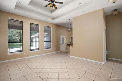 Tiled empty room featuring a tray ceiling and ceiling fan | Image 3