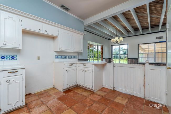 Kitchen with tasteful backsplash, a notable chandelier, white cabinets, hanging light fixtures, and ornamental molding | Image 14
