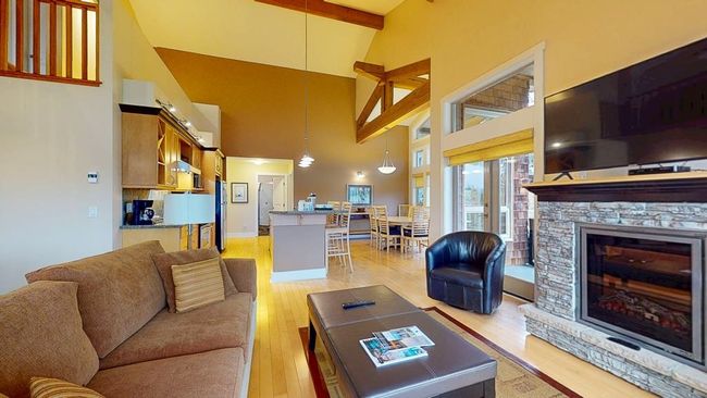 Living room featuring a stone fireplace, beam ceiling, light wood-style floors, and high vaulted ceiling | Image 16