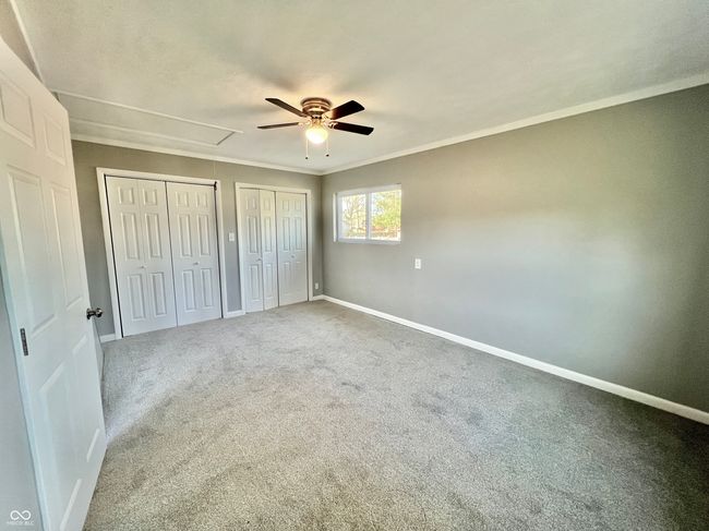 unfurnished bedroom featuring carpet floors, baseboards, attic access, and two closets | Image 12