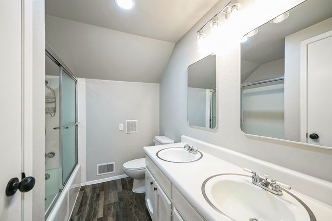 Bathroom featuring vaulted ceiling, visible vents, wood finished floors, and a sink | Image 13