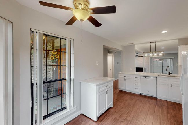 Kitchen featuring white appliances, light wood-style floors, a sink, white cabinetry, and a ceiling fan | Image 15