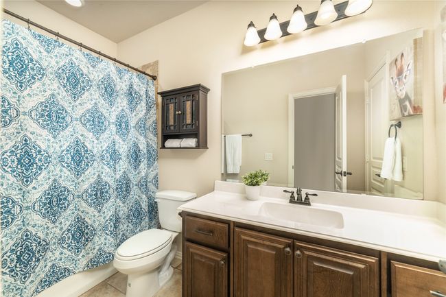 Full bathroom with toilet, tile patterned floors, vanity, and a shower with curtain | Image 28