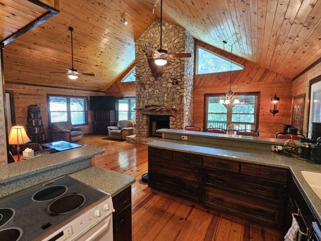 Kitchen featuring electric range oven, wood walls, ceiling fan, wooden ceiling, and wood-type flooring | Image 10