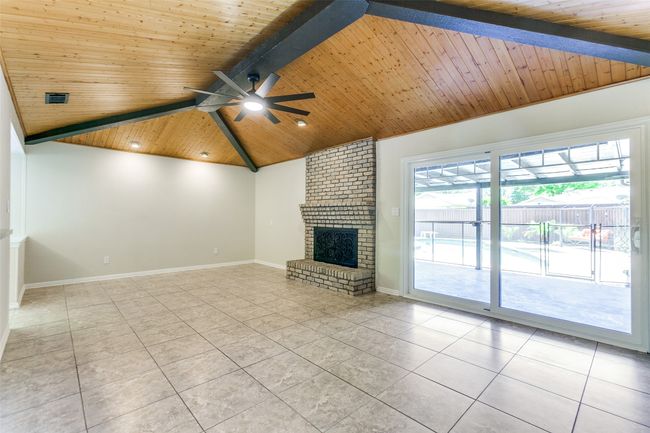 Unfurnished living room with tile patterned floors, wooden ceiling, ceiling fan, and a fireplace | Image 7