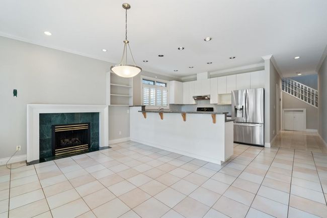 Kitchen with stainless steel fridge, ornamental molding, dark countertops, pendant lighting, and a kitchen breakfast bar | Image 11