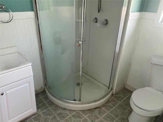 Full bathroom featuring vanity, toilet, tile patterned floors, a stall shower, and wainscoting | Image 4