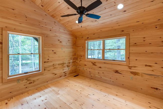Empty room featuring wood ceiling, vaulted ceiling, wood walls, wood finished floors, and ceiling fan | Image 31