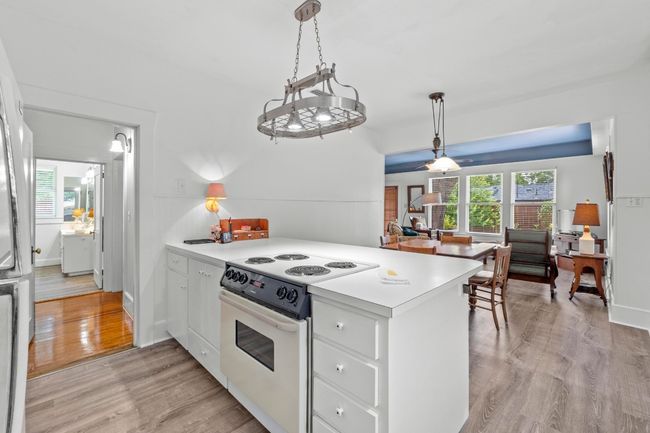 Kitchen with electric cook top and oven peninsula, countertops, wood flooring, and white cabinets | Image 12