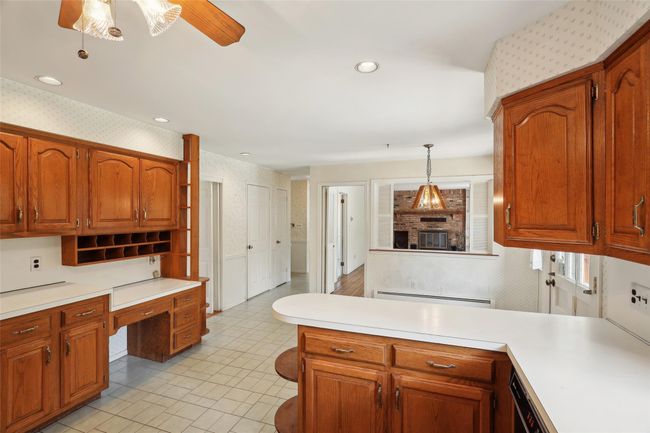 Kitchen featuring a peninsula, built in desk, wallpapered walls, and light countertops | Image 9