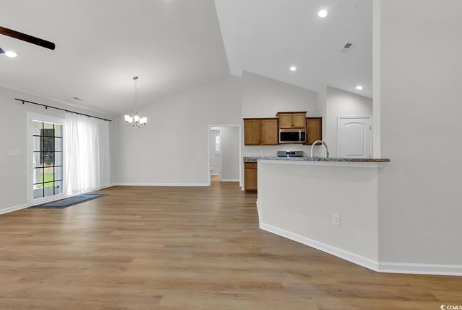 Kitchen featuring appliances with stainless steel finishes, a chandelier, brown cabinets, a ceiling fan, and baseboards | Image 5