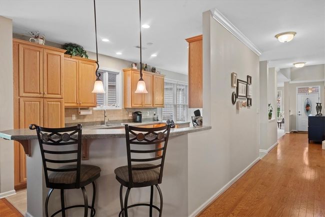 Start your day with your hot cup of coffee at the raised breakfast bar illuminated by two pendant lights. Notice how the pristine hardwoods flow to the front door. | Image 13