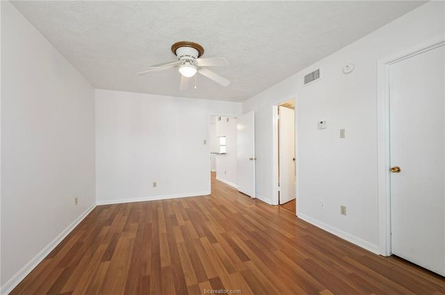Empty room featuring dark wood-type flooring, a textured ceiling, and ceiling fan | Image 9