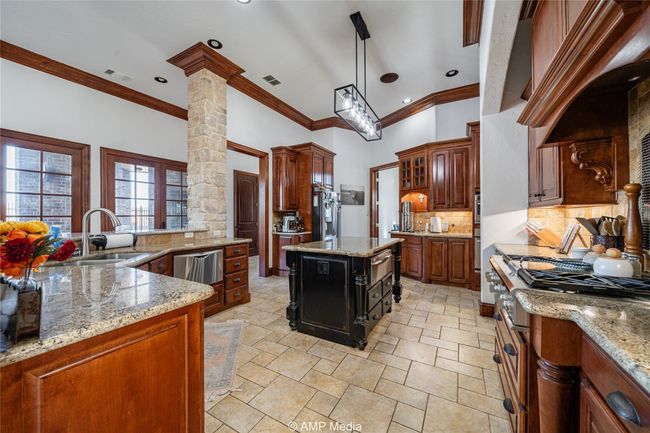 Kitchen featuring stainless steel range, a center island, tasteful backsplash, and light stone counters | Image 12
