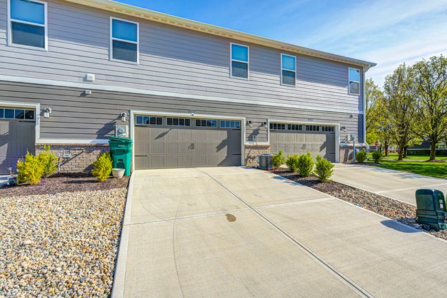view of side of home featuring stone siding, driveway, and an attached garage | Image 32
