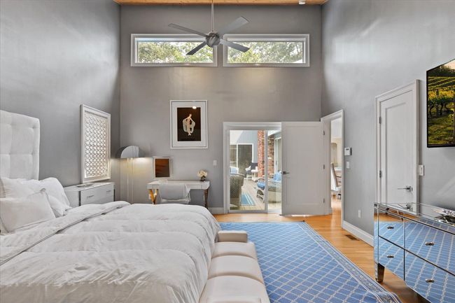 Bedroom featuring a high ceiling, light wood-style flooring, and multiple windows | Image 12
