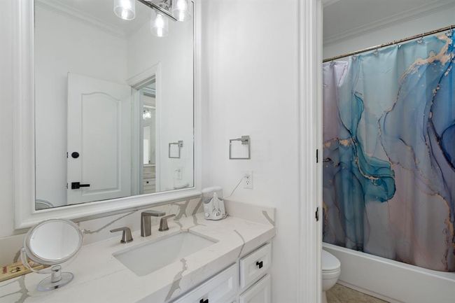 tylish Jack and Jill bathroom with quartz countertops, white cabinetry, and a tub/shower combo. A modern design that offers convenience and elegance. | Image 39