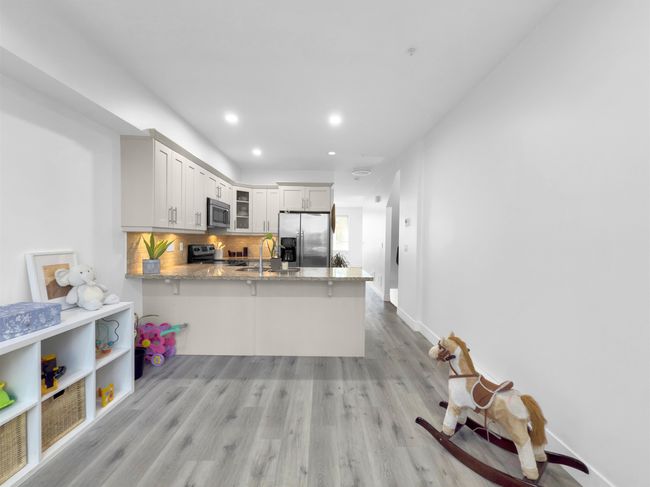 Kitchen with light wood-type flooring, tasteful backsplash, stainless steel appliances, a peninsula, and glass insert cabinets | Image 9