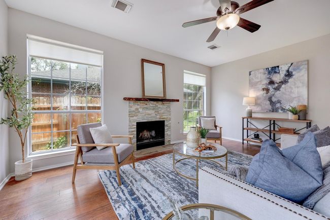 Living area featuring wood finished floors, a stone fireplace, ceiling fan, and baseboards | Image 12