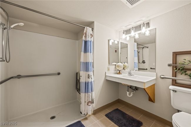 Bathroom with tile patterned floors, visible vents, toilet, and a stall shower | Image 17