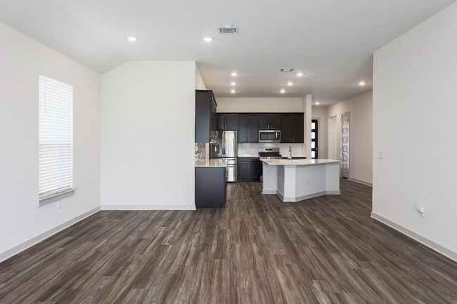 Living room is open to the kitchen featuring stainless steel appliances, light countertops, dark wood-style floors, a breakfast with sink and recessed lighting | Image 6