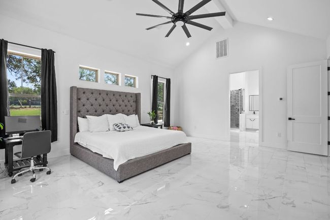 Bedroom with high vaulted ceiling, recessed lighting, beamed ceiling, light tile floors, and ensuite bathroom | Image 14