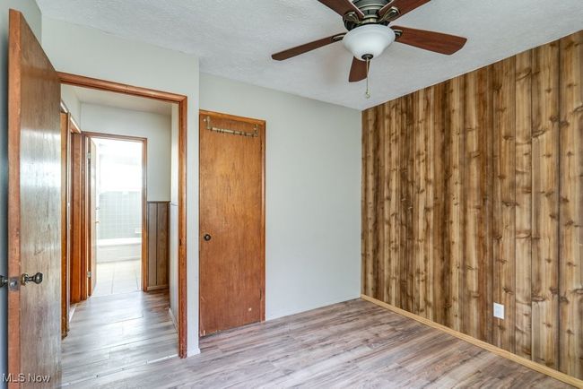 Unfurnished room featuring wood finished floors, a ceiling fan, wood walls, and a textured ceiling | Image 27