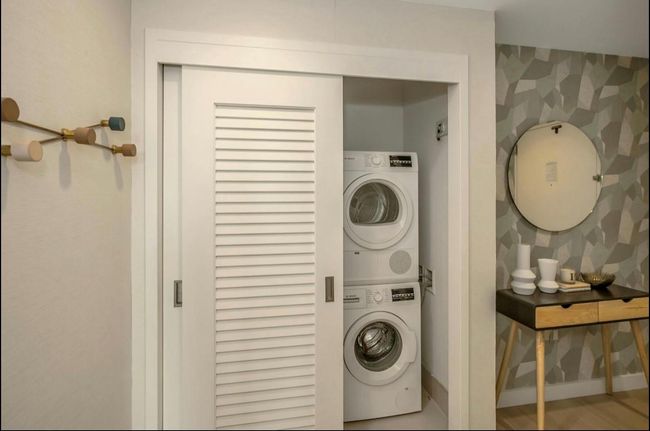 Washroom featuring stacked washer / dryer and wallpapered walls | Image 10