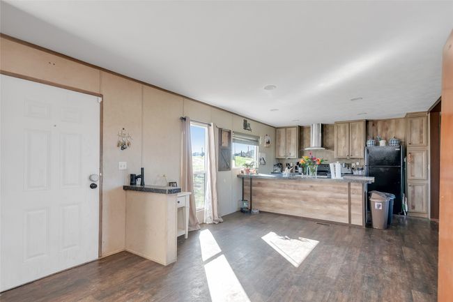 Kitchen featuring dark wood finished floors, freestanding refrigerator, and wall chimney range hood | Image 14