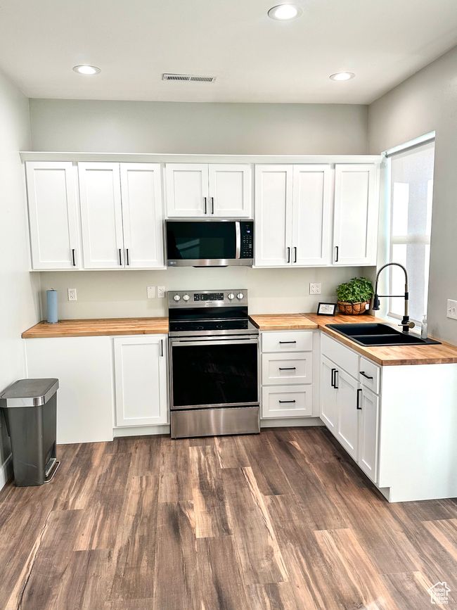 Kitchen with dark wood-style flooring, visible vents, wooden counters, appliances with stainless steel finishes, and a sink | Image 30