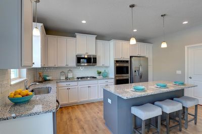 The heart of your home, the kitchen, is perfectly suited for everyday enjoyment and hosting. Quartz countertops, subway tile backsplash, stainless steel double ovens, gas cooktop, microwave, & dishwasher. Photo of model home; Colors and options vary. | Image 3