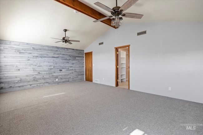 Spare room with a ceiling fan, wooden walls, carpet flooring, and an accent wall | Image 19