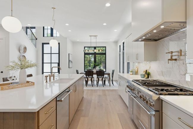 Kitchen featuring appliances with stainless steel finishes, light wood-style flooring, a sink, light countertops, and extractor fan | Image 9