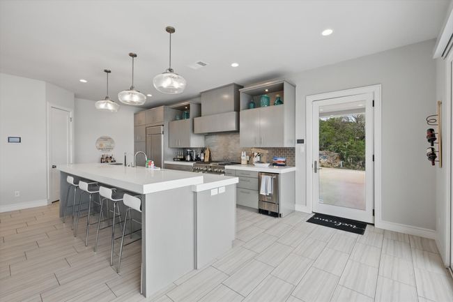 Kitchen featuring visible vents, tasteful backsplash, a center island with sink, light countertops, and a breakfast bar | Image 15