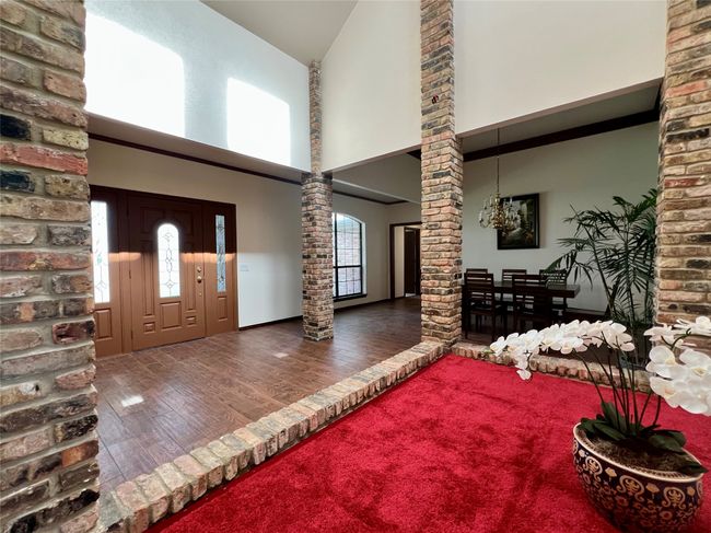 Entryway with decorative columns, wood finished floors, high vaulted ceiling, and a chandelier | Image 9