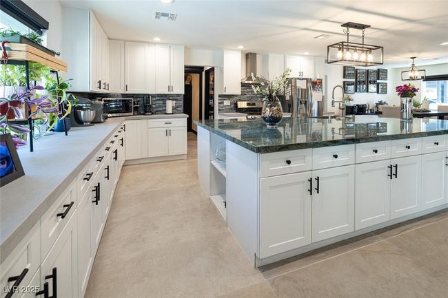 Kitchen with open shelves, backsplash, a spacious island, stainless steel appliances, and wall chimney range hood | Image 16