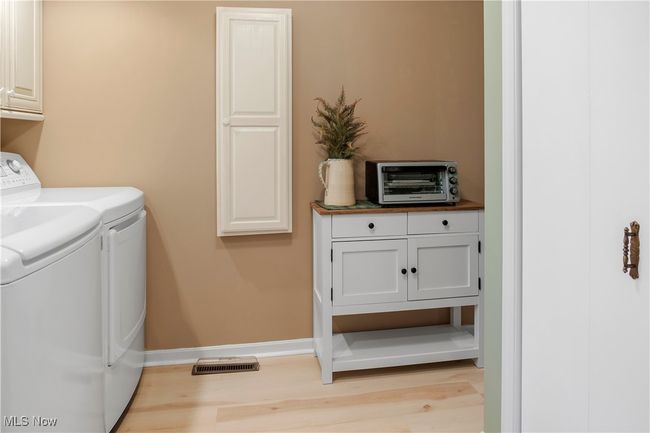 Laundry area with light wood-type flooring, a toaster, washer and clothes dryer, and cabinet space | Image 14